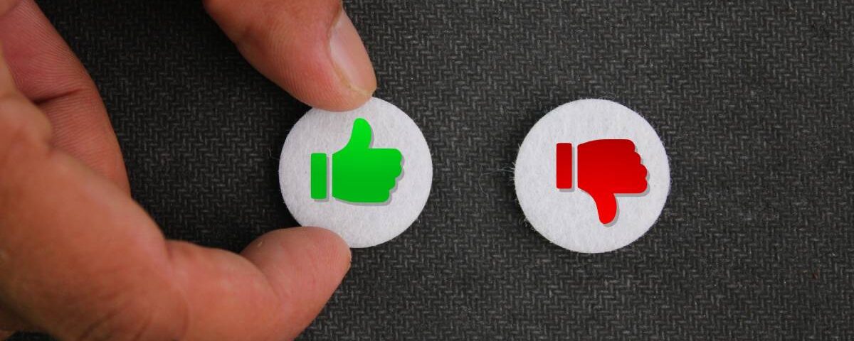 A close-up of a hand touching a thumbs-up button. There is a thumbs-down button next to it.