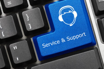 A close-up of a black keyboard where the enter key has been replaced with a blue button that says "Service and Support."