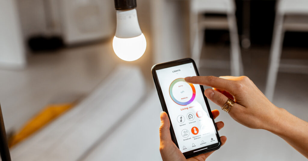 A person out-of-frame using a smartphone app to adjust the color of the bright white light bulb in front of them.